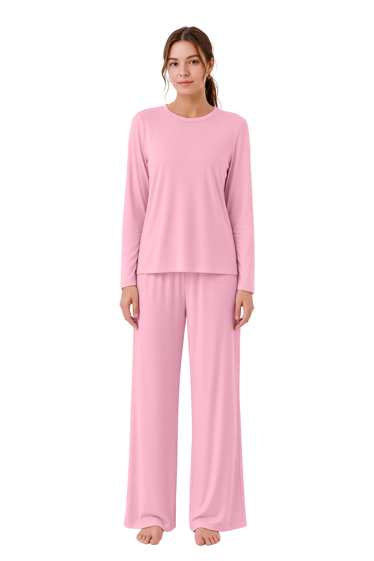 A woman modeling a light pink two-piece pajama set consisting of a long-sleeve crewneck top and matching wide-leg pants, photographed against a solid white background.