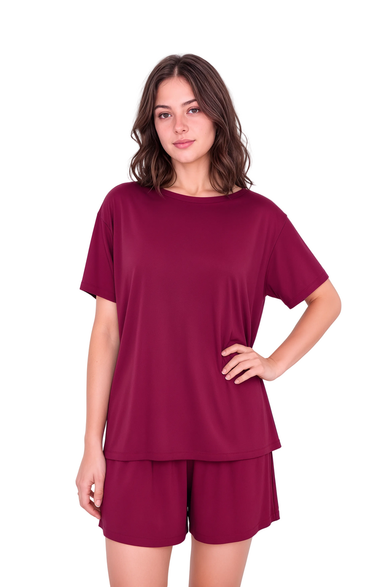 A woman modeling a matching two-piece loungewear set consisting of a short-sleeve crewneck top and matching shorts in a deep burgundy color, set against a plain light background.
